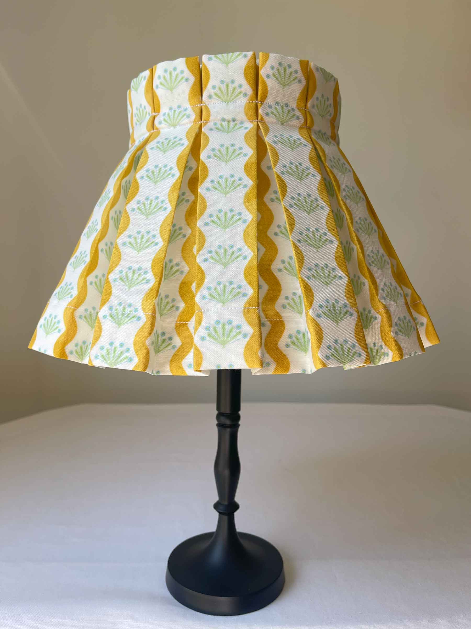 yellow lampshade in box pleat style that give a cottage feel sits beautifully on a white table
