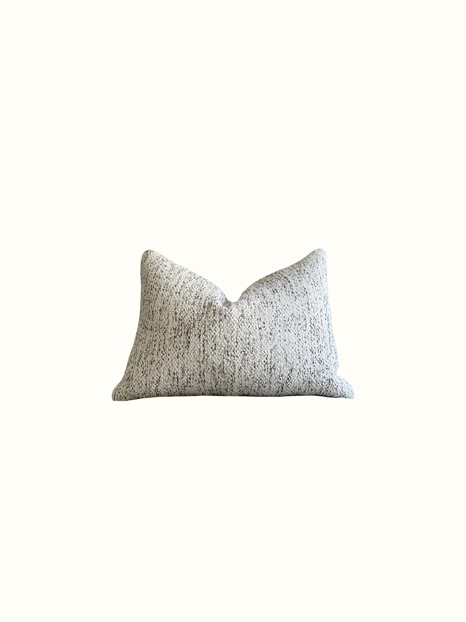 A neural boucle lumbar pillow in black and white interwoven achieving a marble fabric effect