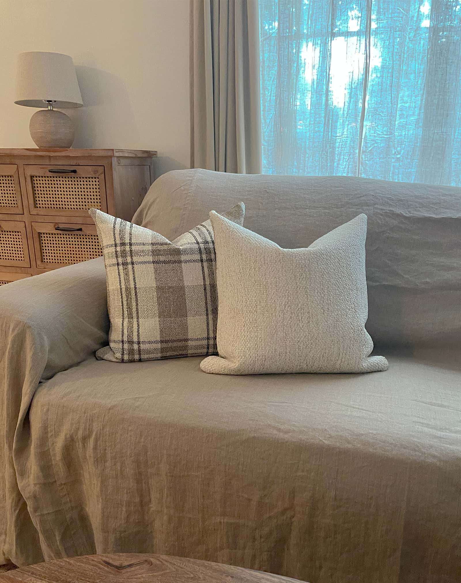 Creamy wheat colored boucle pillow paired with neutral plaid throw pillow for linen sofa creates a cozy space for fall and all seasons