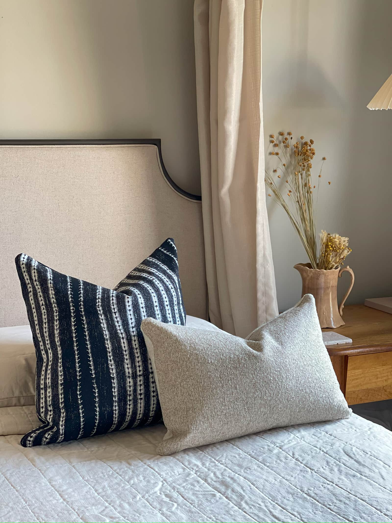 Pillow set for neutral colored bed, featuring a decorative throw pillow in contrasting indigo and white stripes