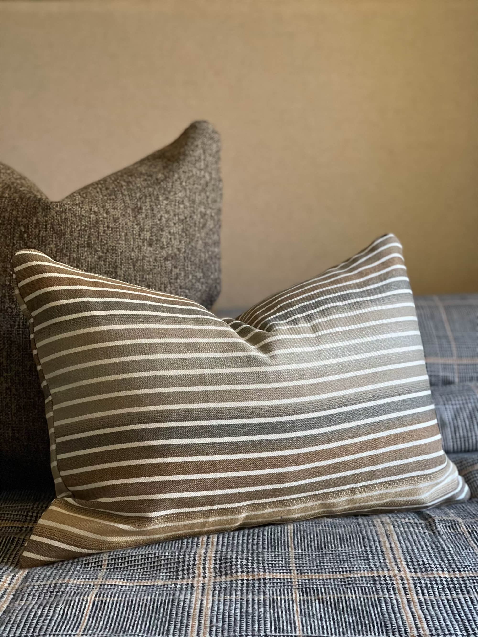 Striped throw pillow for bed in earthy-toned gradient brown color.