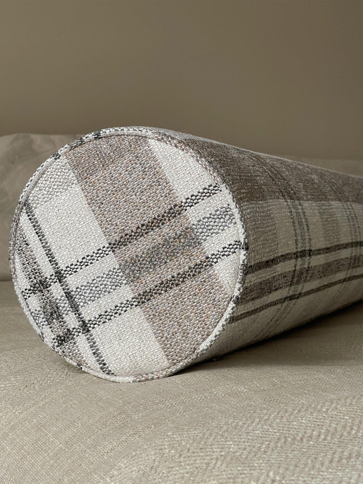 A neutral plaid bolster pillow with firm foam insert adds coziness to the space
