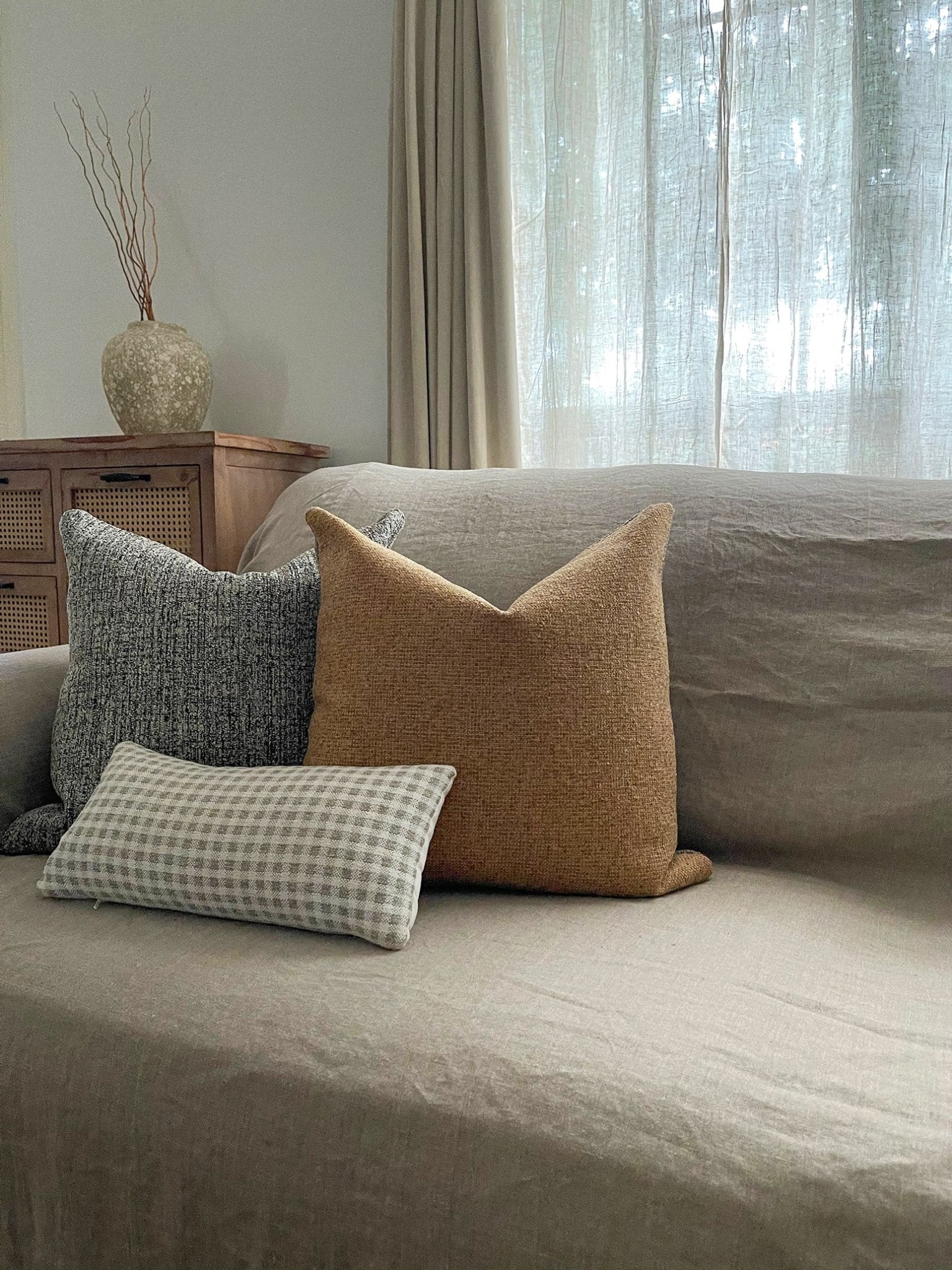 A neutral pillow set for sofa couch features sandy tan boucle throw pillow styled in midcentury modern rustic setting