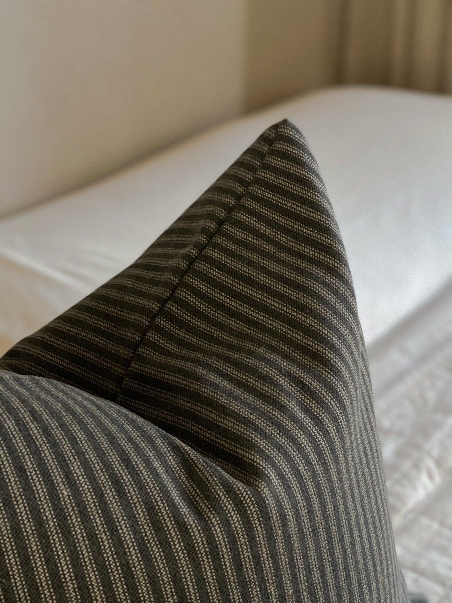 A close-up view of the black ticking striped throw pillow on neutral bedding