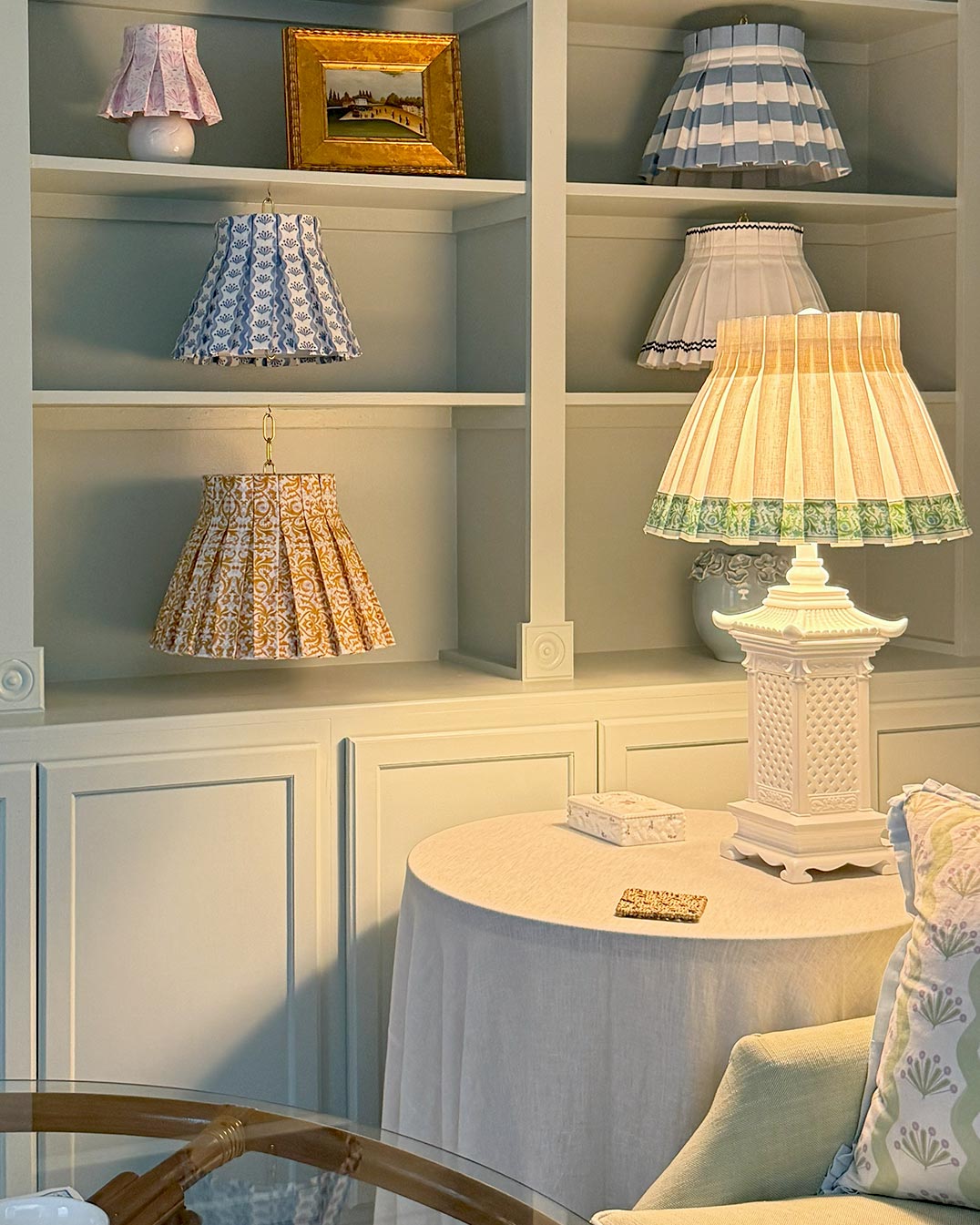 Shelves with various lampshade skirts and a table with a lamp in a room at Cielle Home setting.